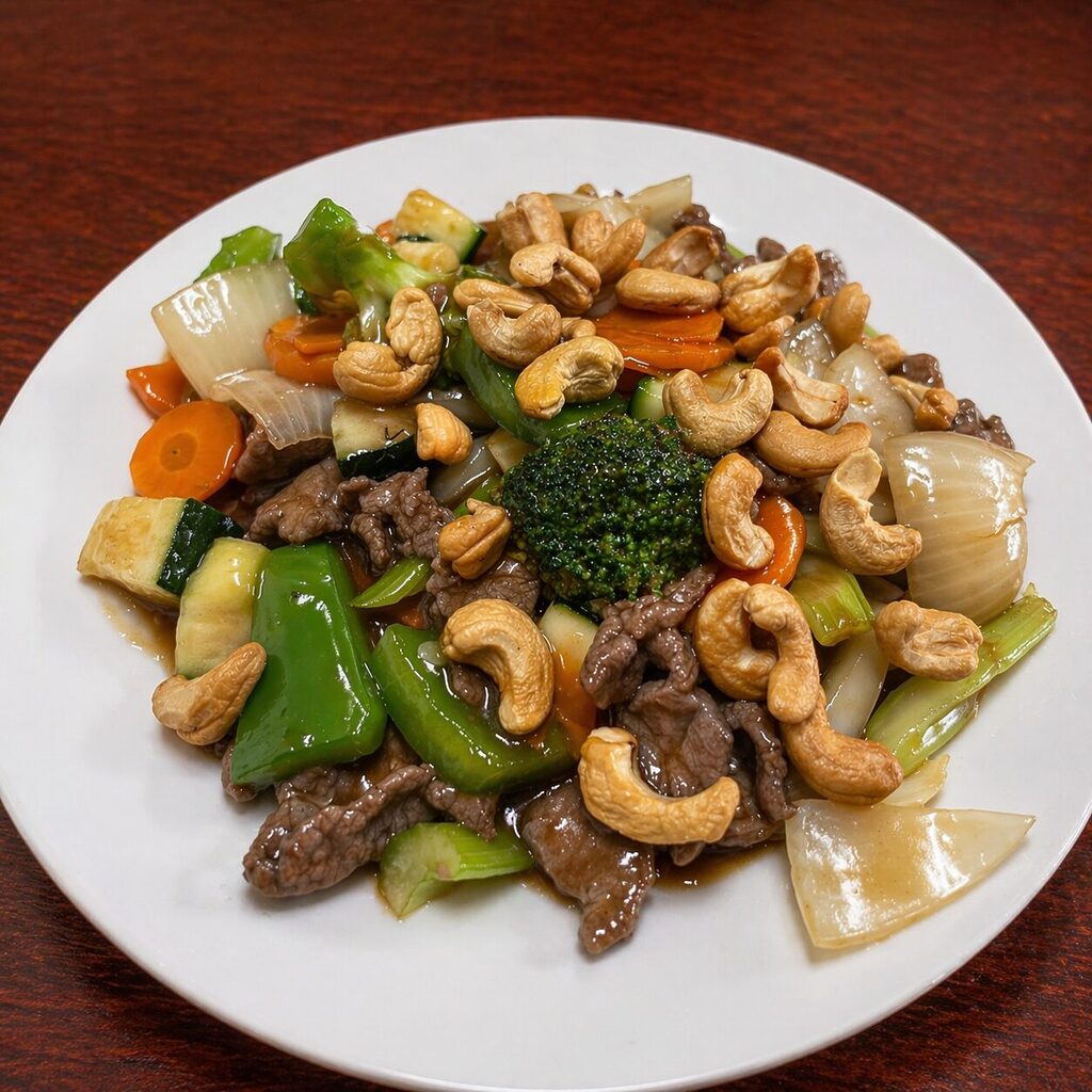 Stir-fried beef with broccoli, carrots, zucchini, onions, and cashews on a white plate