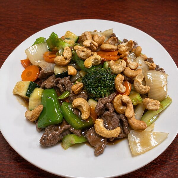 Stir-fried beef with broccoli, carrots, zucchini, onions, and cashews on a white plate