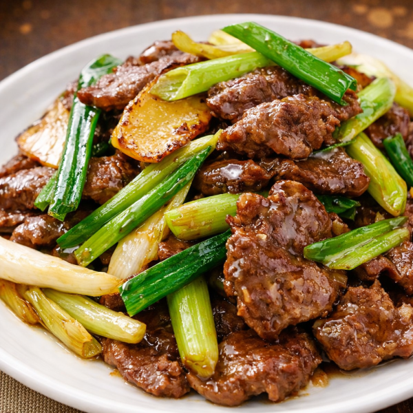 Stir-fried beef with scallions on a white plate