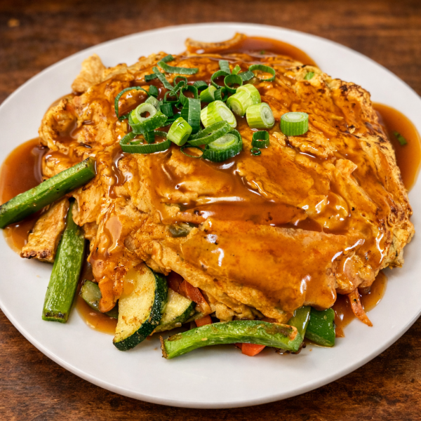 Egg foo young topped with brown gravy and sliced green onions, served with stir-fried zucchini and carrots