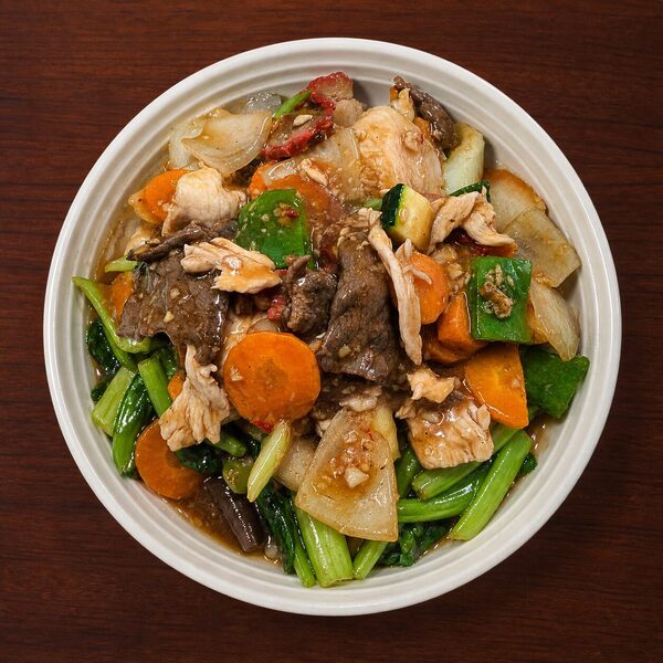 Stir-fried beef and chicken with carrots, zucchini, and leafy greens in a savory sauce