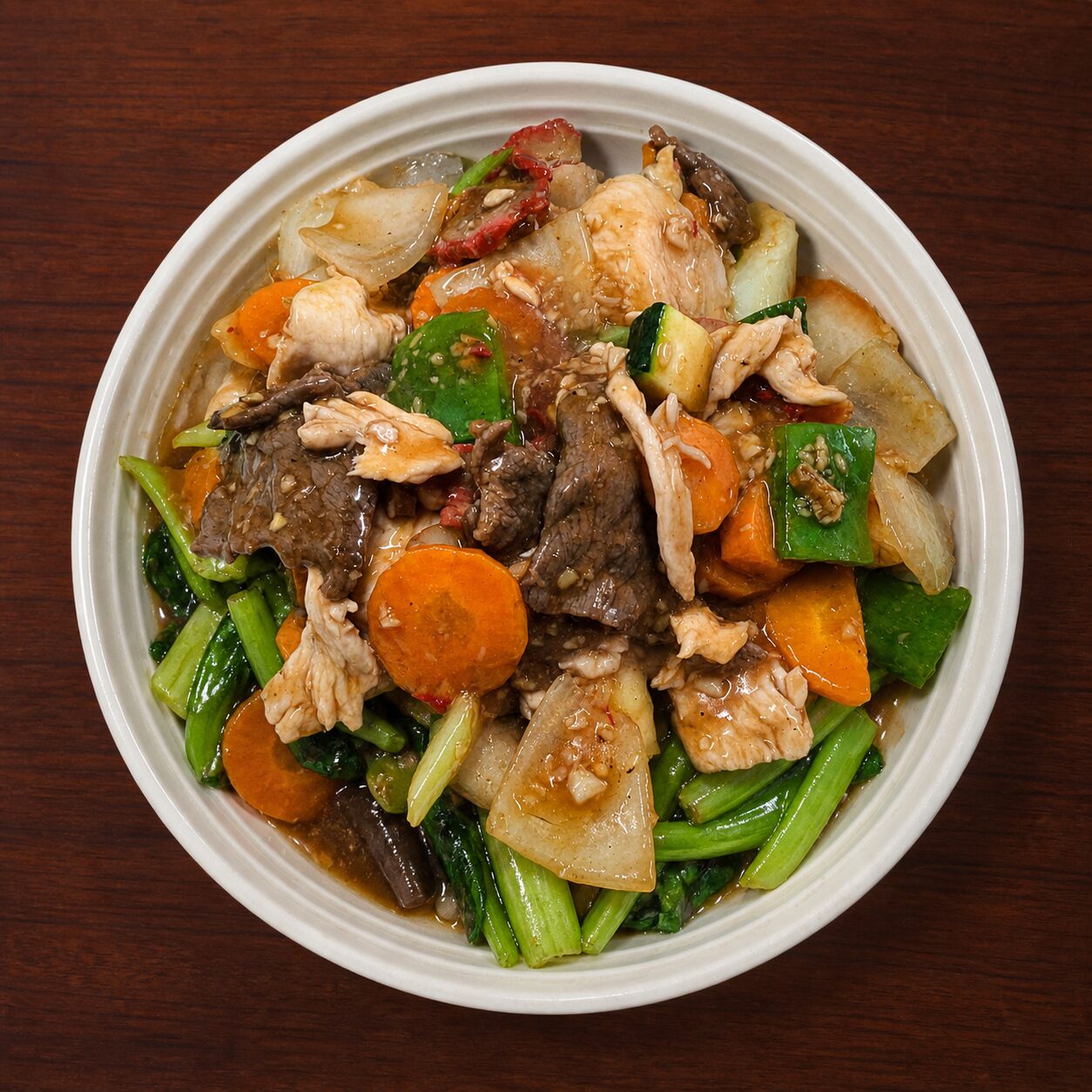 Stir-fried beef and chicken with carrots, zucchini, and leafy greens in a savory sauce