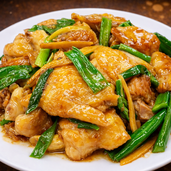 Stir-fried chicken pieces glazed in a savory sauce with fresh green onions and ginger strips