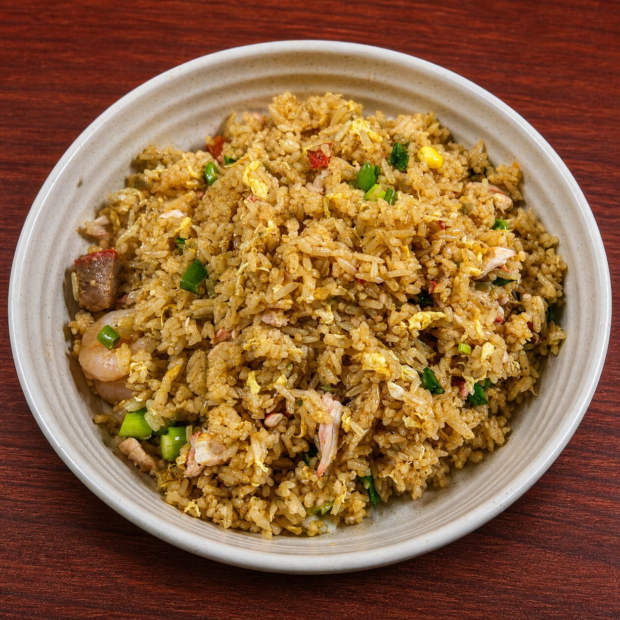 Bowl of fried rice with shrimp, meat, egg, and green onions