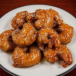 A plate of sesame shrimp glazed in a brown sauce