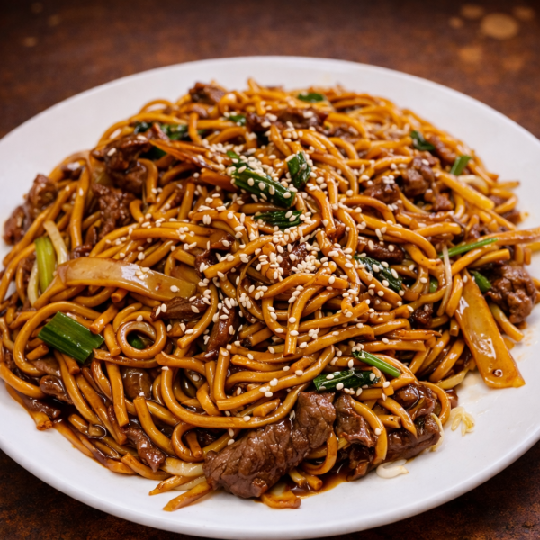 Stir-fried beef lo mein noodles with green onions and sesame seeds on a white plate