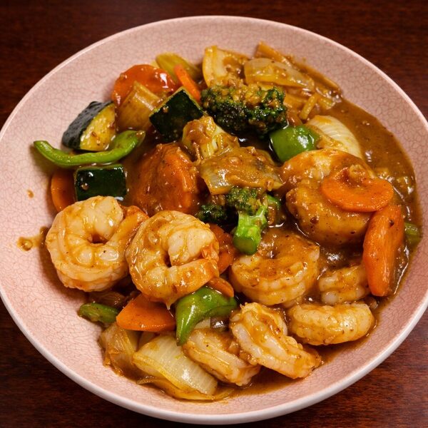 Shrimp stir-fry with broccoli, carrots, zucchini, and onions in a savory brown sauce served in a pink bowl