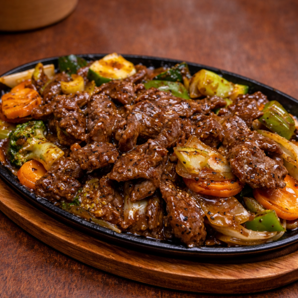 Sizzling black pepper beef stir-fry with broccoli, carrots, and onions served on a hot cast iron platter