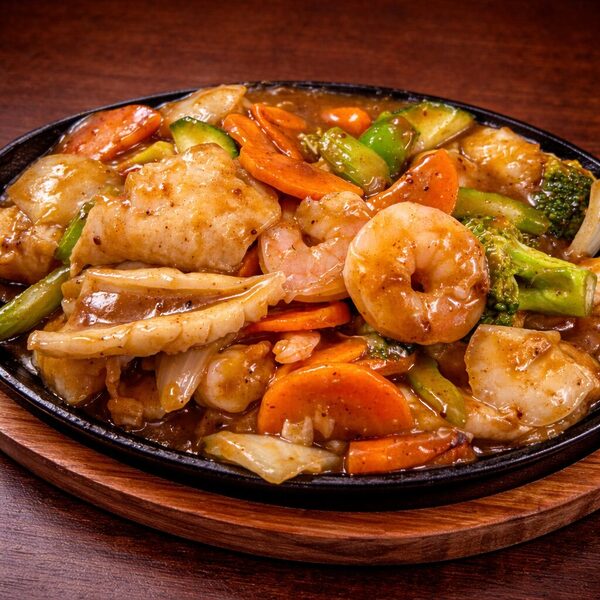 Stir-fried seafood with shrimp, squid, and vegetables in a savory sauce served on a hot iron plate
