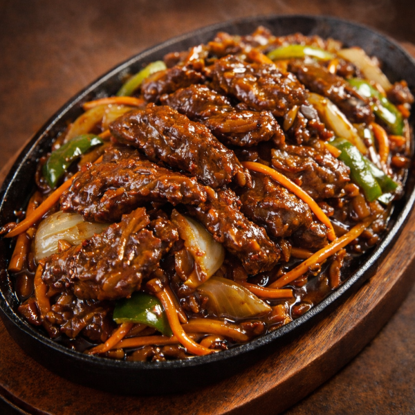 Sizzling beef stir-fry with bell peppers, onions, and carrots served on a hot cast-iron platter