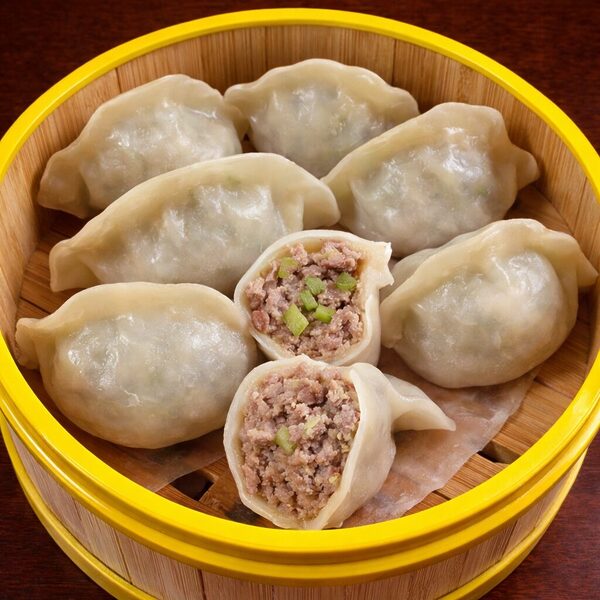 Steamed dumplings with pork and scallion filling served in a bamboo steamer