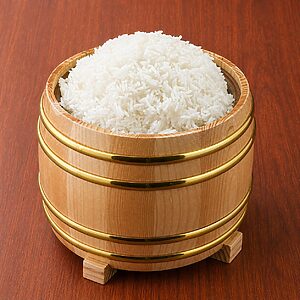 A mound of cooked white rice served in a wooden bucket with gold-colored metal bands