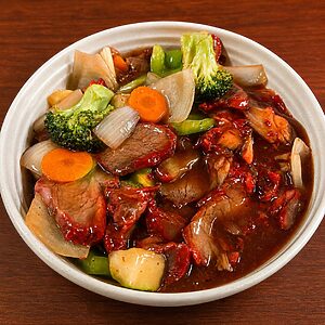 Bowl of stir-fried char siu pork with broccoli, carrots, and onions in a savory brown sauce