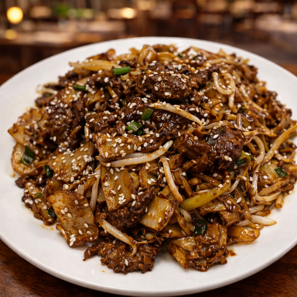 Stir-fried beef with flat rice noodles, bean sprouts, and scallions, garnished with sesame seeds