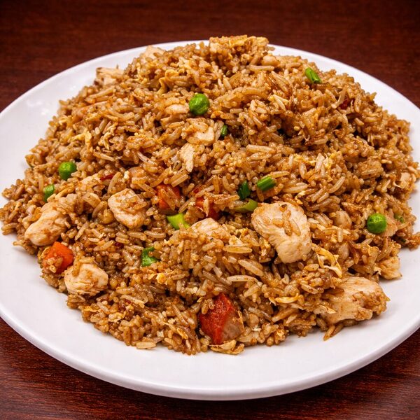 A plate of chicken fried rice with peas and carrots