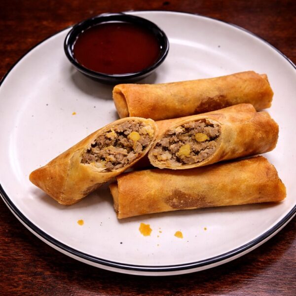 Crispy fried egg rolls filled with ground meat, served on a plate with a side of dipping sauce